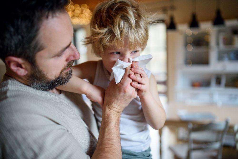 Flunssainen ja kuumeinen lapsi isänsä sylissä