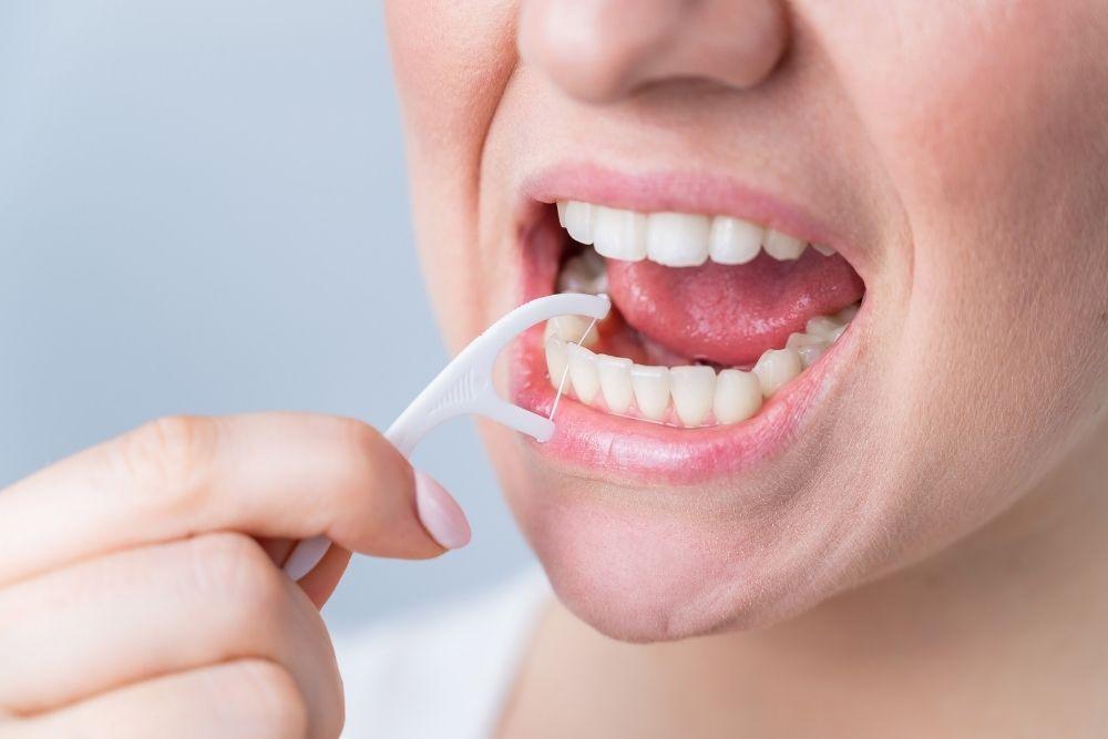 Nainen käyttää hammaslankainta parodontiitin ehkäisyssä.