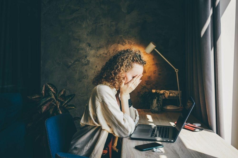Stressaantunut nainen kädet naamalla tietokoneen ääressä