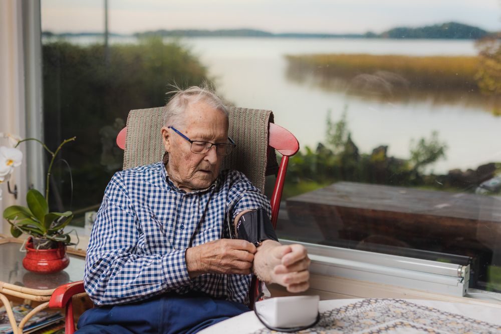 Mies laittaa verenpainemittaria käteen.