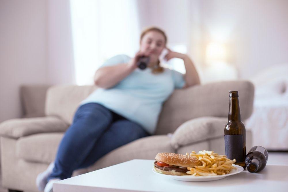 Roskaruokaa pöydällä, taustalla ylipainoinen nainen